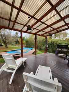 a pavilion with white chairs and a pool at nisueñes in Belén de Escobar