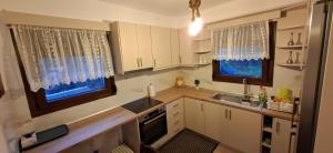 a kitchen with white cabinets and a sink and two windows at Family House in Platamonas