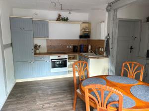 eine Küche mit blauen Schränken, einem Tisch und Stühlen in der Unterkunft Ferienwohnung Eldeidyll in Neu Kaliß