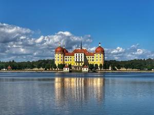 a large yellow building with red domes on the water at Bungalow am Wald in Coswig
