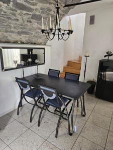 a black dining room table with chairs and a chandelier at Fienile in Avegno +10 photos