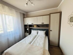 a bedroom with a bed with white sheets and a window at Apartament 29 in Orăştie