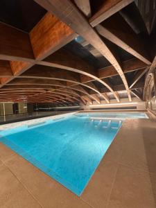 an indoor swimming pool with blue water and wooden ceilings at Afrodite Luxury Residence & Spa in Pescara