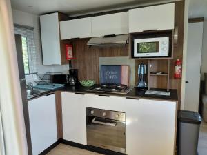 a kitchen with a stove and a microwave at Mobil home Salsa in Litteau +12 photos