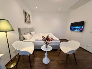 a bedroom with a bed and two chairs and a table with flowers at Apartmenthaus Döbeln Zentrum 01 in Döbeln