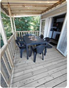 a wooden deck with a table and chairs on it at Mobil home Salsa in Litteau