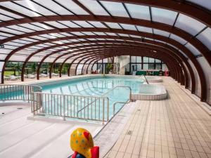 a swimming pool in a building with an arcade at Mobil home Salsa in Litteau