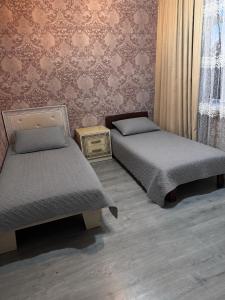 a bedroom with two beds and a wall with wallpaper at Apartment in Lankaran in Lankaran
