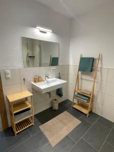 a bathroom with a sink and a mirror and a chair at Apart Alma in Pfunds +8 photos