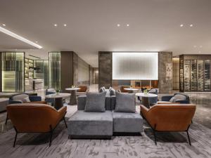 a lobby with a couch and chairs and tables at Novotel Kunshan Yangcheng Lake in Kunshan