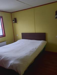 a bedroom with a bed with white sheets and a window at Casa rayen in Puerto Natales