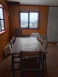 a room with a wooden table and chairs and a window at Casa rayen in Puerto Natales