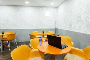 a conference room with yellow chairs and a laptop on a table at H2 Fuenlabrada in Fuenlabrada