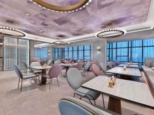 a restaurant with tables and chairs and purple ceilings at Mercure Danzhou Yangpu Seaview in Dongshan