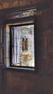 a window in a brick building with a curtain at Hotel Altamira in Santillana del Mar