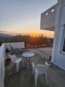 a patio with a table and chairs and the sunset at infinity sky stay in episkopi-heraklion