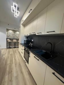 a kitchen with black and white cabinets and a sink at Luxury Vibes in Şelimbăr