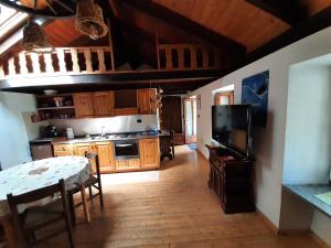 a kitchen with wooden cabinets and a table and a television at Sotto il Cielo, Balcone panoramico sul borgo di Ingria in Ingria +29 photos