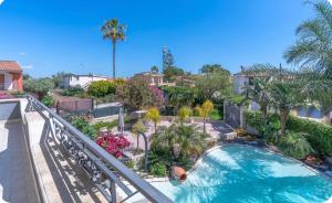 a balcony with a swimming pool and palm trees at Villa Joel in Fontane Bianche