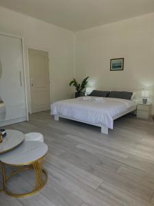 a white bedroom with a large bed and a table at Camino apartmani in Dračevo