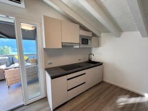 a kitchen with white cabinets and a view of a patio at Felicita Cascata Terrace with Lake View in Lecco
