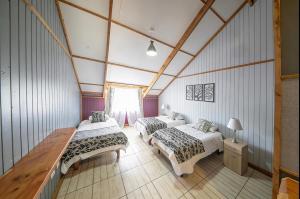 a room with three beds and a table in it at Apart Hotel y Cabañas Valle Exploradores in Puerto Tranquilo