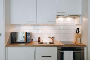 a kitchen with white cabinets and a sink and a microwave at Apartment in Engelberg in Engelberg