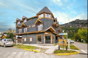a large house with a gambrel roof on a street at Apart Hotel y Cabañas Valle Exploradores in Puerto Tranquilo