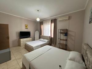 a hotel room with two beds and a television at Vila Era in Shëngjin