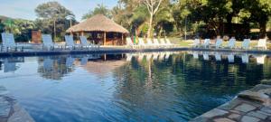 a pool of water with chairs and a gazebo at Complexo Turístico Canaã in Nobres