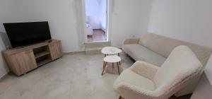 a living room with a couch and a tv and a stool at mala Atina in Petrovaradin