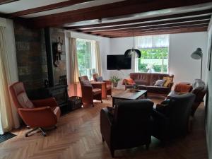 a living room with leather furniture and a tv at het Uitzicht in Elspeet