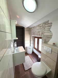 a bathroom with a white toilet and a stone wall at Tea Rooms III in Bale