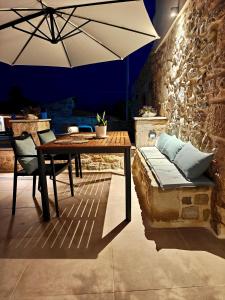 a table and a bench with an umbrella in a room at Ellotis Stone Retreat in Áyioi Dhéka