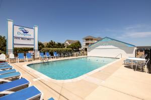 a large swimming pool with chairs and a sign at Dolphin Oceanfront Motel - Nags Head in Nags Head