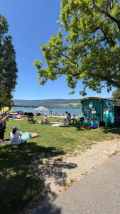 Eine Gruppe von Menschen sitzt am Strand im Gras. in der Unterkunft Oumaya in Erlach