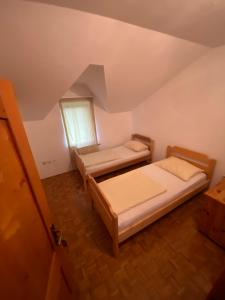 an attic room with two beds and a window at Estrada Cazin in Ostrožac