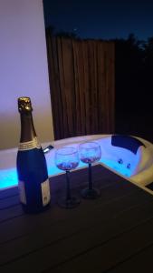 a bottle of champagne and two glasses next to a bath tub at Maisonnette des trois frontières in Richwiller