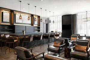 a bar in a restaurant with leather chairs and tables at AC Hotel Lenexa City Center in Lenexa