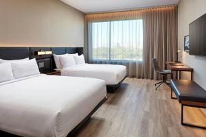 a hotel room with two beds and a desk at AC Hotel Lenexa City Center in Lenexa