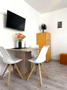 a table with two white chairs and a television on a wall at STAY - City W32 in Friedrichshafen