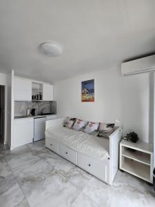 a white bedroom with a bed and a kitchen at Cozy Seaside Studio with Private Parking in Nice