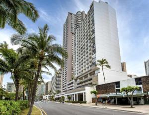 a street in front of a tall building with palm trees at Inn on The Park in Honolulu