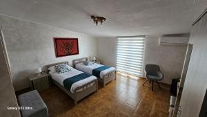 a bedroom with two beds and a chair and a window at Torre Serena B&B in Atella