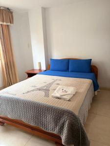 a bedroom with a large bed with blue pillows at Hotel Manhattan City in Duitama