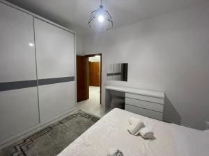 a white bedroom with a bed and a desk at Dedi Apartment 2 in Shkodër