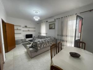 a bedroom with a bed and a living room with a table at Dedi Apartment 2 in Shkodër