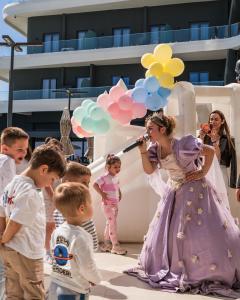 a woman in a purple dress singing into a microphone at Ilyonis Hotel & Spa in Shëngjin +149 photos