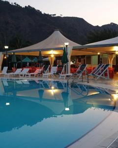 ein Swimmingpool mit Liegestühlen und einem Zelt in der Unterkunft Villaggio Cala Verde in Copanello