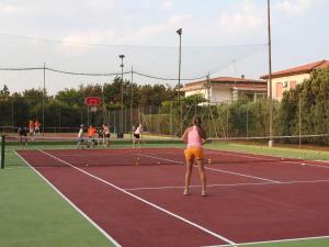Eine Frau spielt Tennis auf einem Tennisplatz in der Unterkunft Villaggio Cala Verde in Copanello
